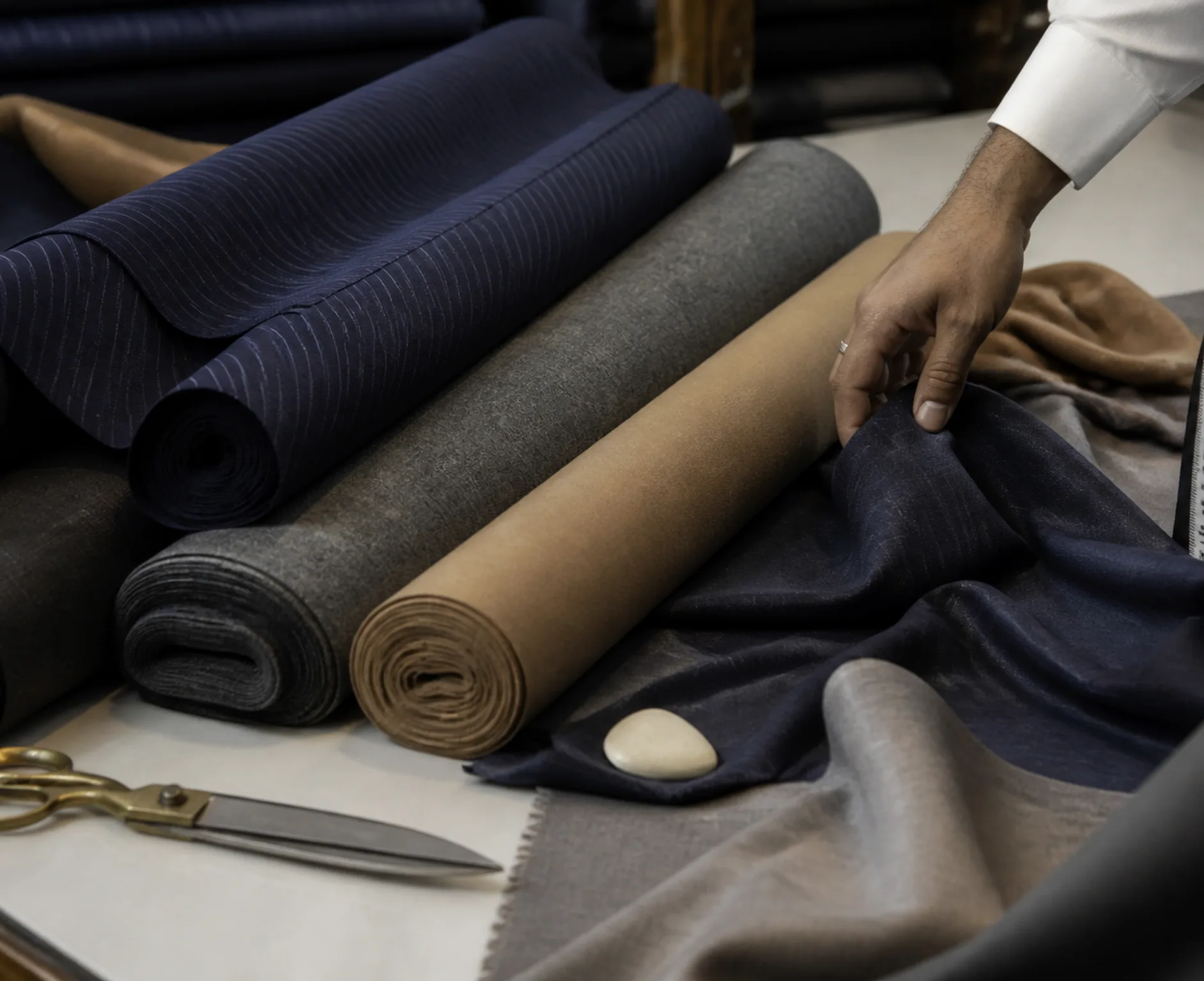 Premium wool and cashmere fabric rolls with tailoring tools on a cutting table